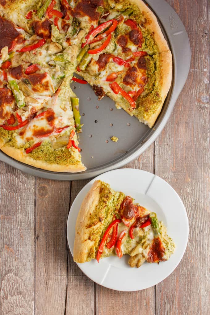 Broccoli pizza on tray and slice of pizza on white plate