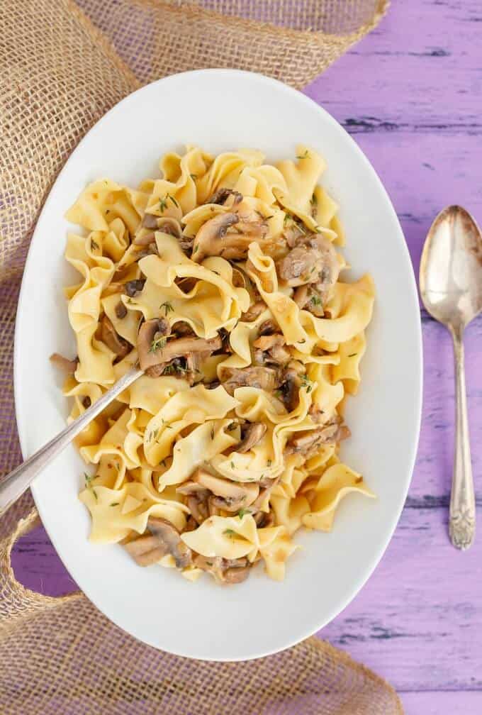 Mushroom Stroganoff on white plate with fork, spoon on purple table