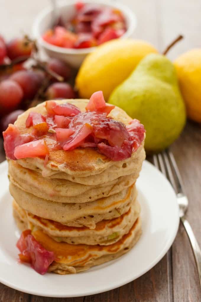 Pear Pancakes with Grape Sauce  on white plate, pears, grapes, cherries in the background#pear #pancakes