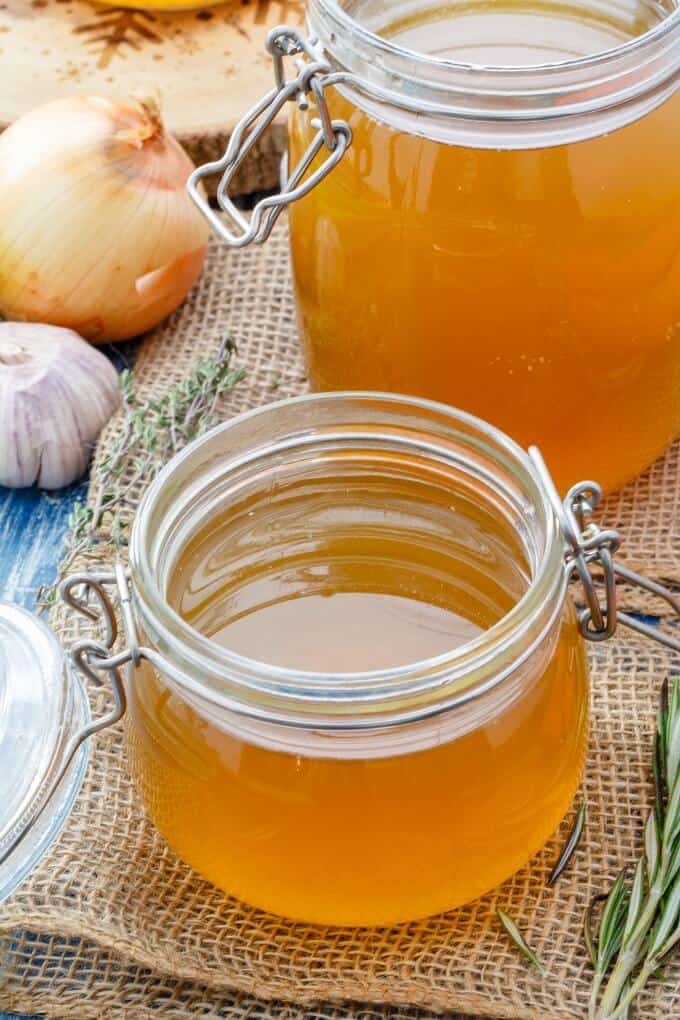 Tutorial: Homemade Chicken Stock in glass jars with onion,garlic and herb on the  table