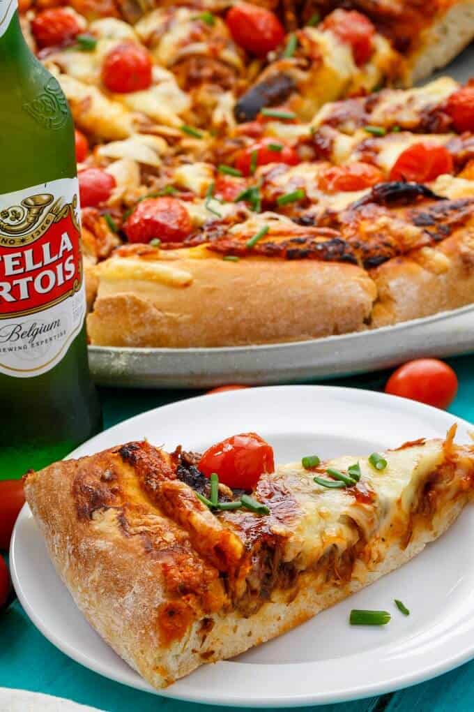 BBQ Pulled Pork Pizza using Leftovers on tray, slice on white plate next to bottle of beer