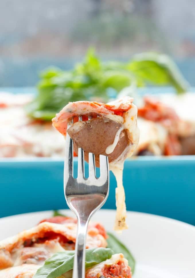 Pizza Macaroni and Cheese using Creamer Potatoes picked by fork on white plate, blue baking pot int the background