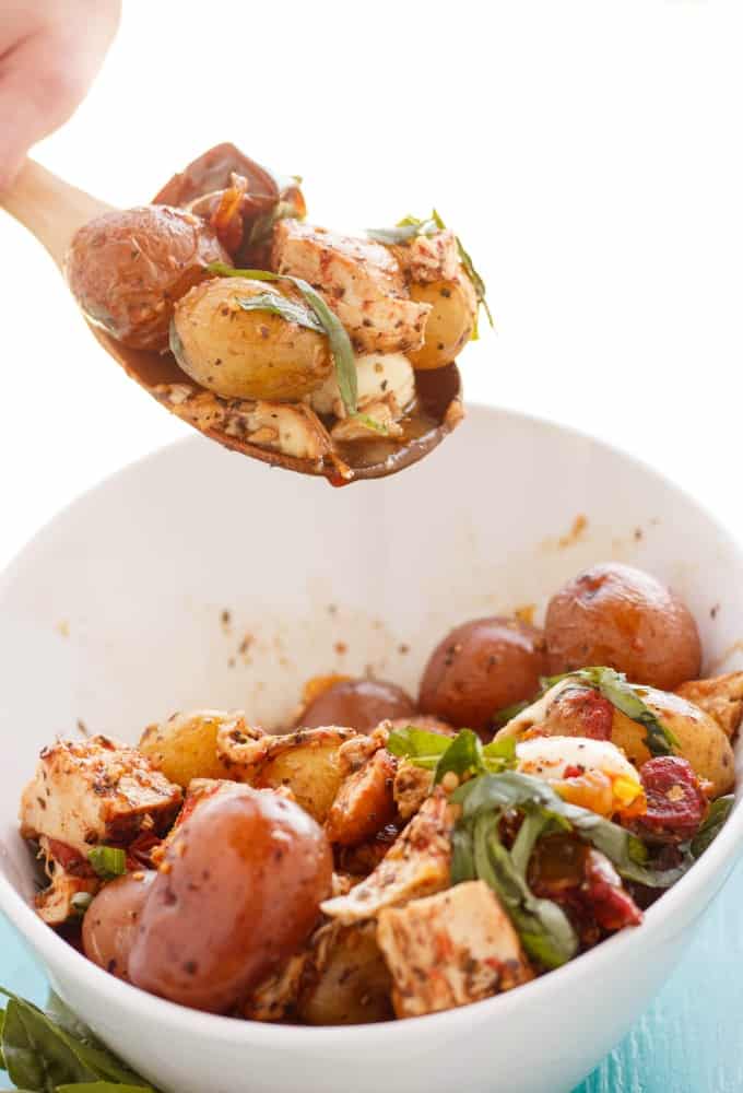 Roasted Potato and Chicken Caprese Salad in white bowl picked by wooden spatula #chicken