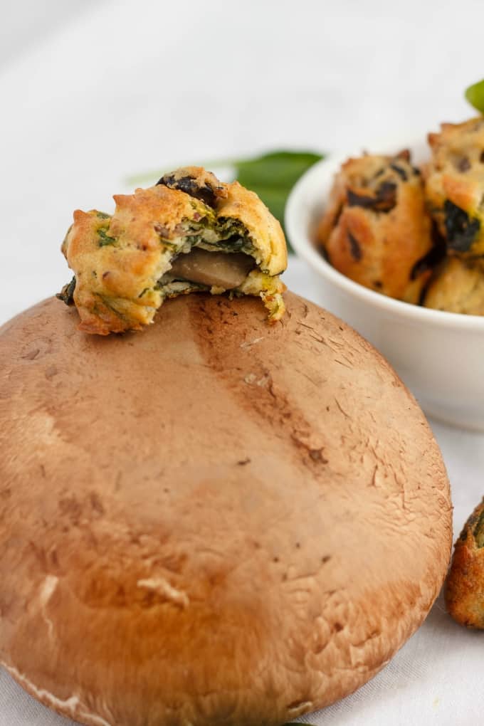 Mushroom and Spinach Puff half eaten on mushroon, bowl of puffs in the background