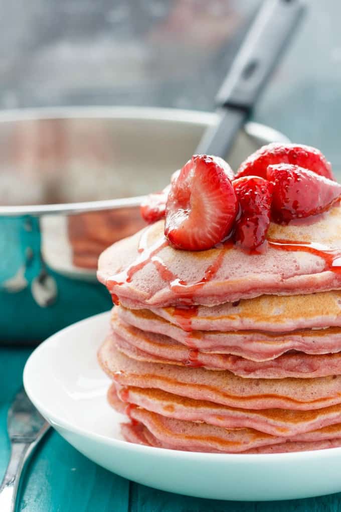 Strawberries and Cream Pancakes on white plate, pot with spatula in the background