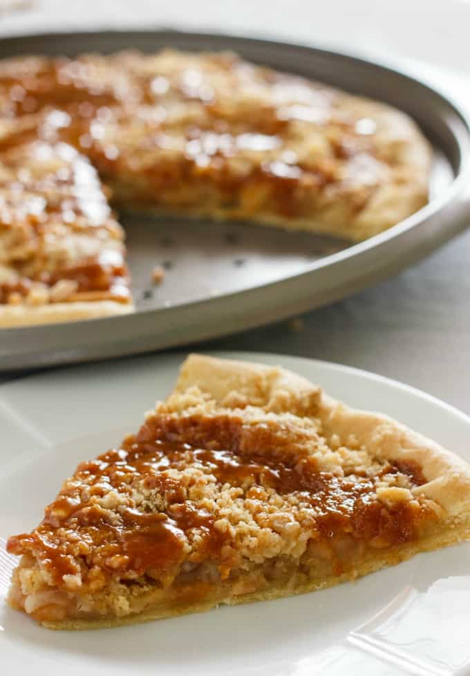 Apple Crisp Pizza slice on white plate, rest of pizza on tray