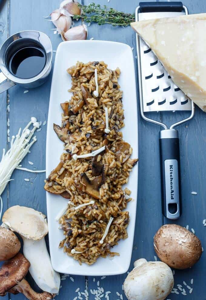 Balsamic Mushroom Risotto on white tray with on black table with mushrooms, cheese,grater, garlic, herbs and sauce