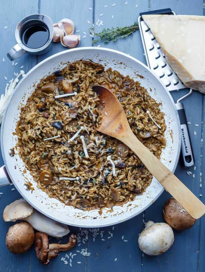 Balsamic Mushroom Risotto on pan with wooden spatula on gray table with grater, cheese, garlic, sauce, mushrooms, herb