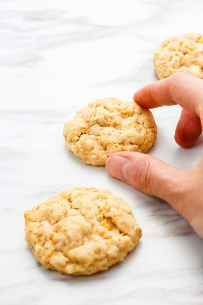 Forest Ranger Cookies on white background, one cookie touched by hand