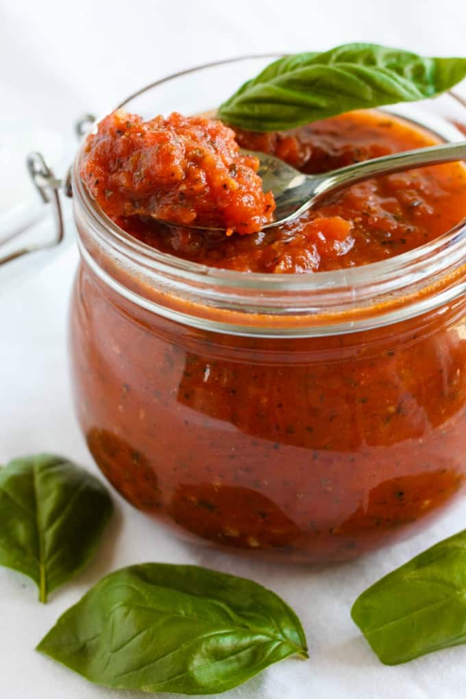 Herb pizza sauce in glass jar with spoon