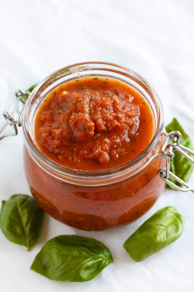 Herb Pizza Sauce in glass jar with herbs spilled around