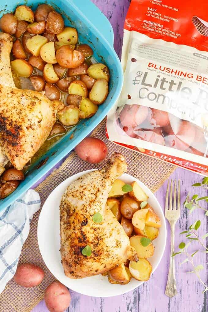 One-Pan Lemon Chicken Leg Quarters with Creamer Potatoes on white plate and in blue baking pot on purple table with sack of potatoes, fork, herbs