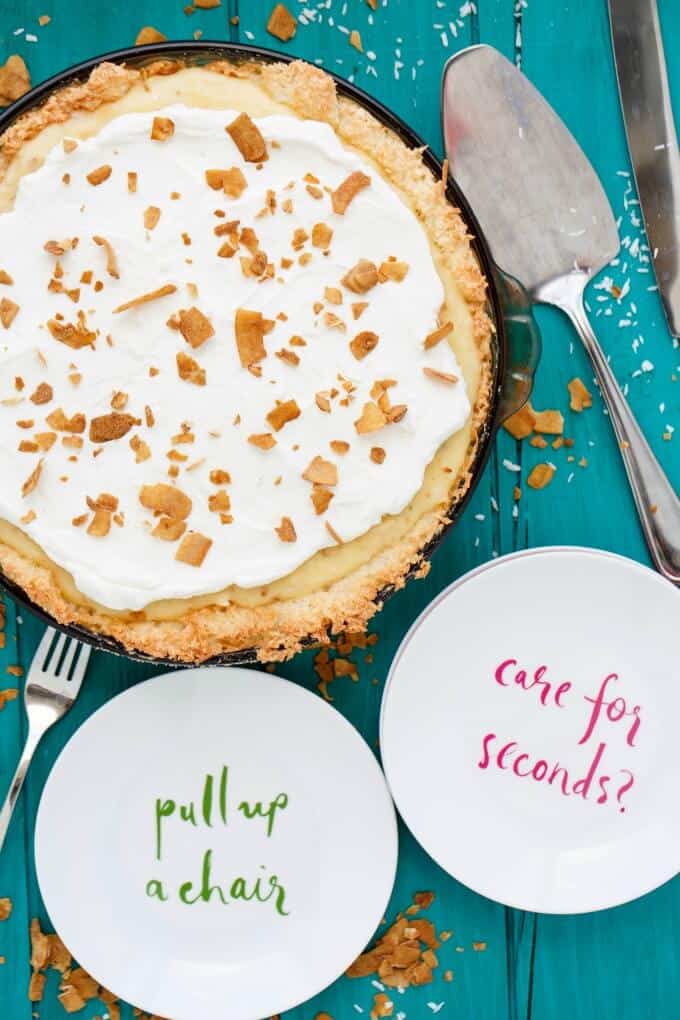 Gluten-Free Coconut Cream Pie on tray on blue table with spatula, fork and two white plates with text