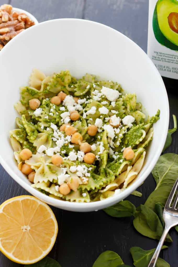 Spinach Sauce with Chickpeas and Walnuts with pasta in white bowl on gray table with lemon, fork and spinach#pasta #vegan