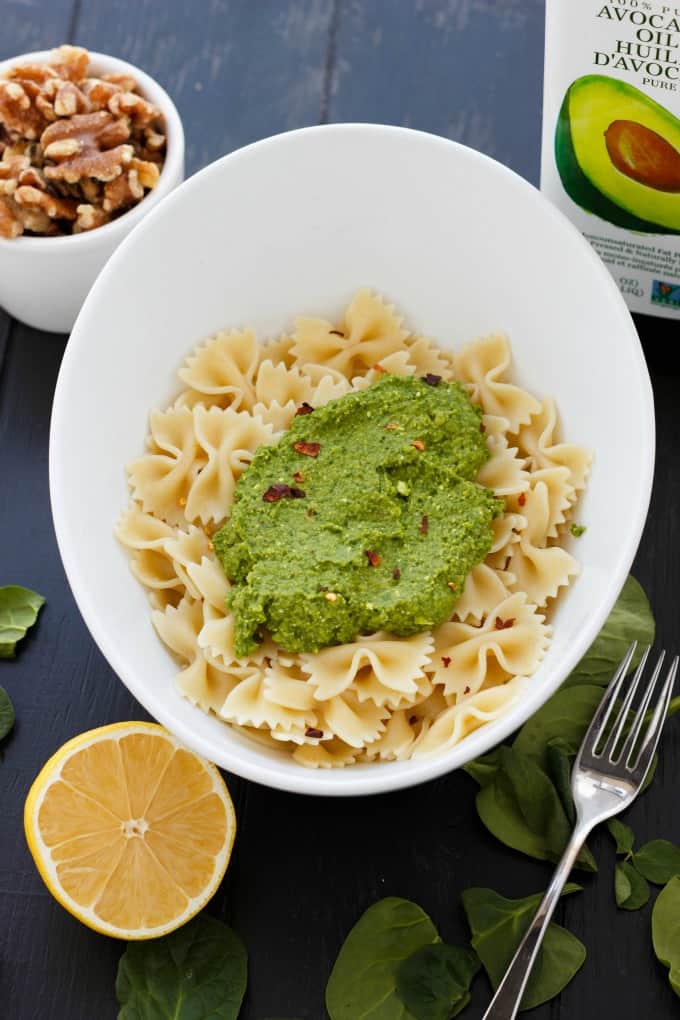 Spinach Sauce with Chickpeas and Walnuts with pasta in white bowl on gray table with lemon, fork, spinach, bowl of nuts#spinach #sauce