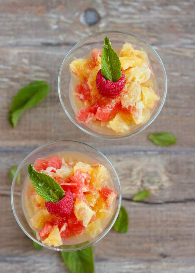 Fresh Fruit Salad using Leftover Fruit and Simple Syrup in glass cups on wooden table with herb leaves