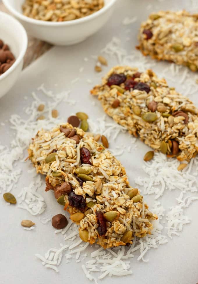 Three Ingredient Banana Granola Bars on white table cloth, ingredients in white bowls