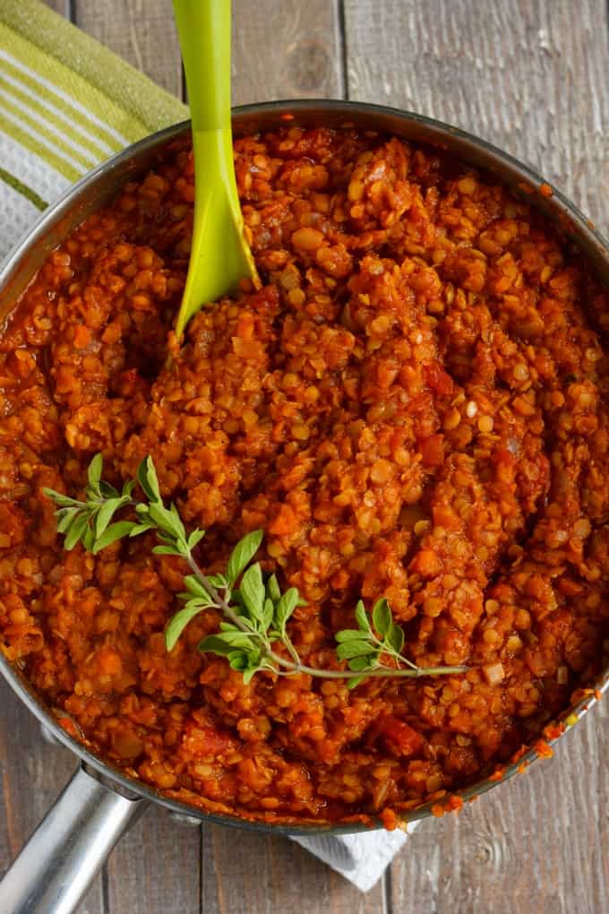 Vegetarian Lentil Bolognese Sauce in pan with green spatula and herb on the top