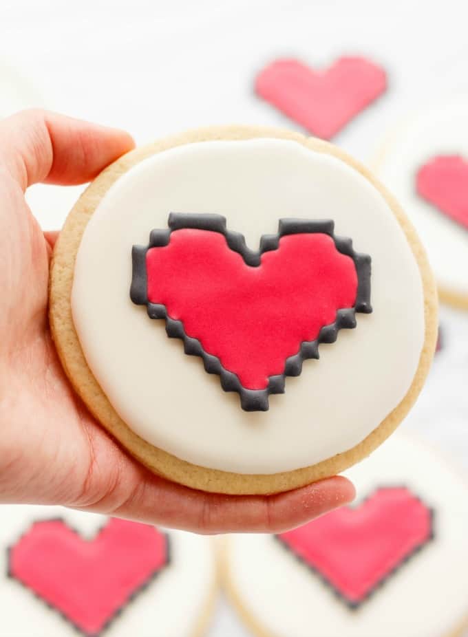 8 bit heart cookie held by hand