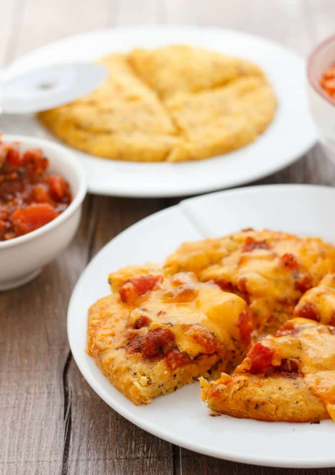 Lentil Pizza Crusts  on white plates, sauce in small bowl on wooden table