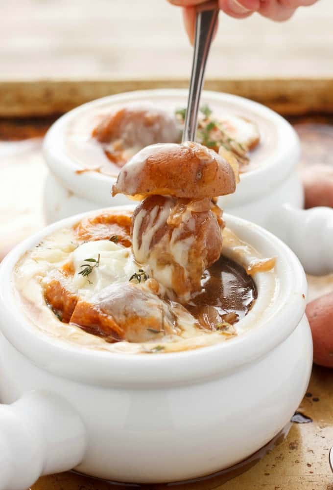 French Onion Soup with Potatoes in white bowls, potatoe picked by spoon#soup