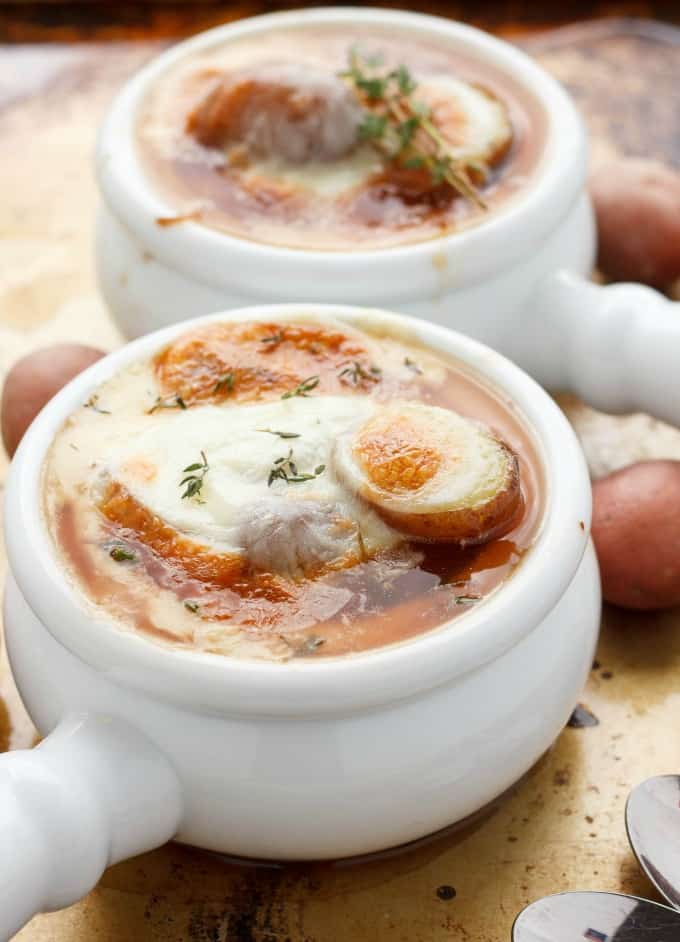 French Onion Soup with Potatoes in white bowls, potatoes and spoons on the table#vegetarian