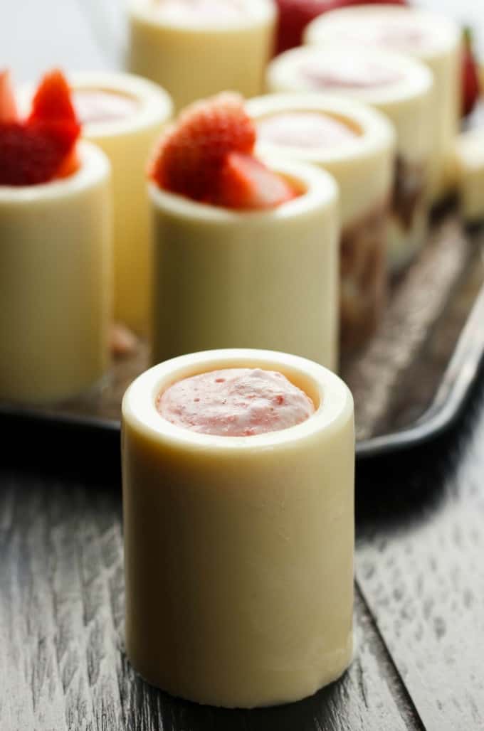 White Chocolate Shot Glasses with Strawberry Mousse on brown tray and black table#chocolate