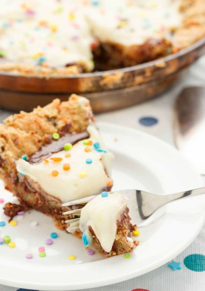 Birthday Cake Cookie and Pudding Pie slice on white plate cutted by fork, rest of cake on tray in the background#dessert