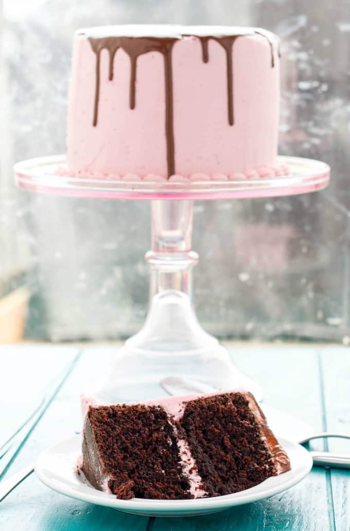 Chocolate Cake with chocolate frosting on glass tray, slice of cake on white plate