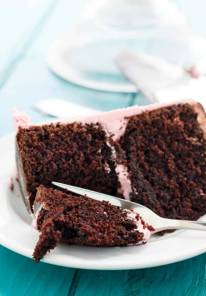 Chocolate Cake slice on white plate with fork on blue table