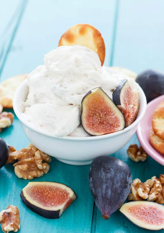 Farm Boy Fig and Walnut Cream Cheese Dip in white bowl on blue table with figs, walnuts and crackers