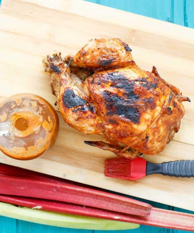 BBQ Whole Chicken with Rhubarb BBQ Sauce  on wooden pad with red brush, sauce in container and rhubarb