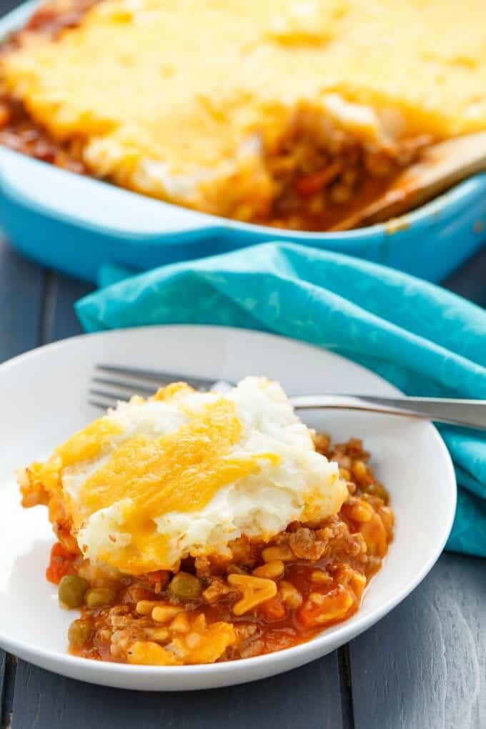 Easy Shepherd's Pie with Campbell's Soup in white bowl with fork on blue table with napkin and baking pot