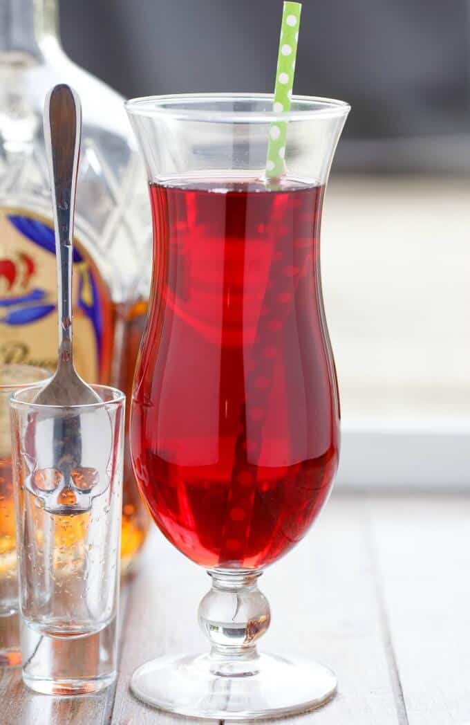 The Executioner drink in glass cup with straw next to glass shot with spoon