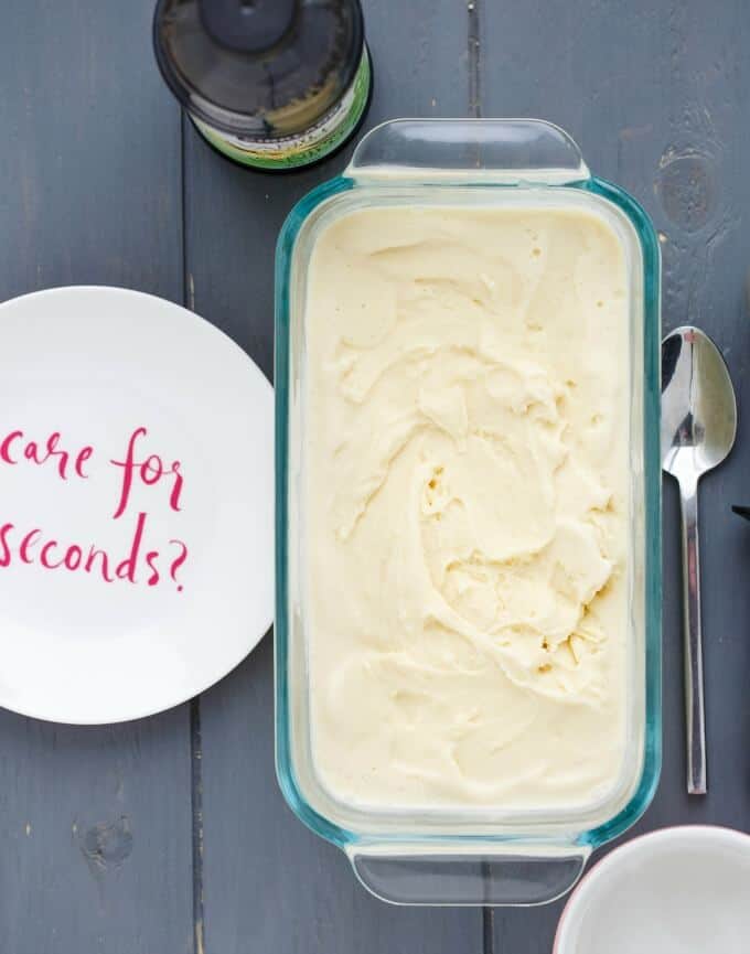 Basic Vanilla Ice Cream  in glass container on gray table with spoon, white plate