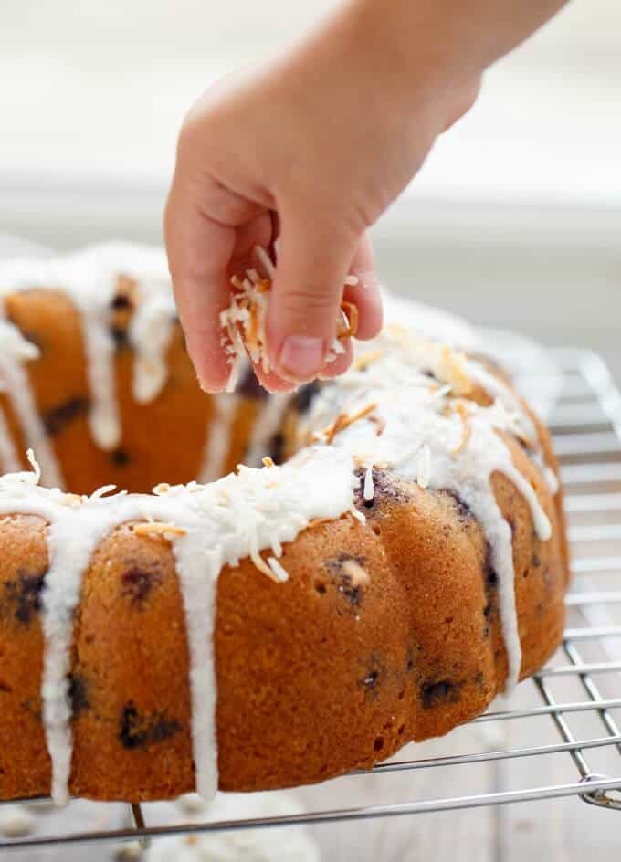 Blueberry Boy Bait Bundt Cake with Toasted Coconut sprinkled by hand on baking grid