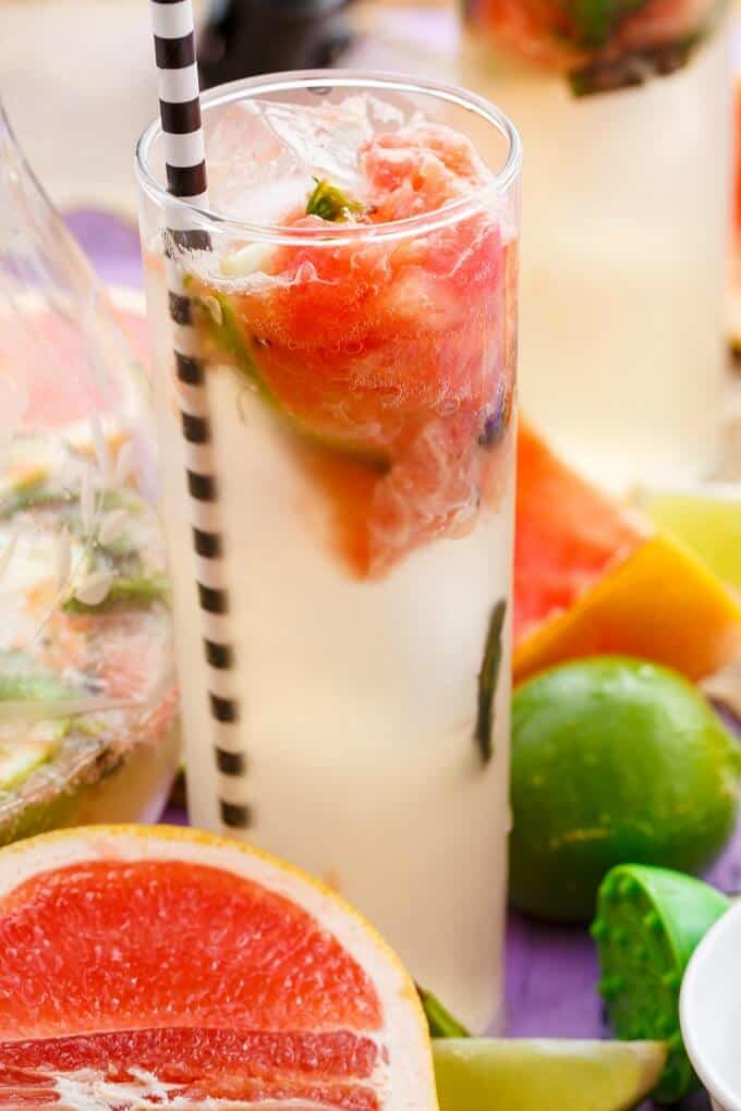 Broiled Grapefruit Mojito in glass cup with straw with limes and grapefruits on the table