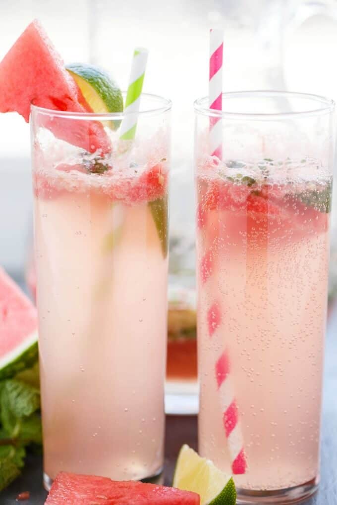 Watermelon Mojitos in glass cups with straws, slices of melon and limes