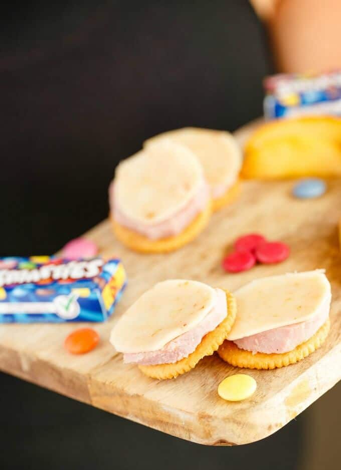 Homemade Lunchables with Ham on wooden pad with candy, hold by human