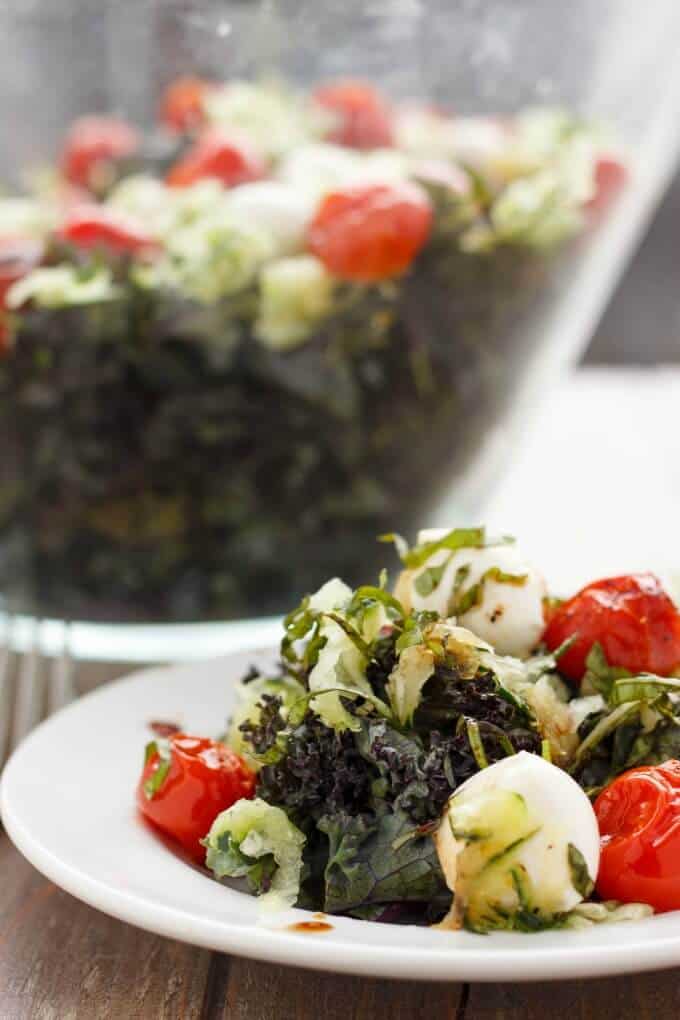 Roasted tomato, cucumber and bocconcini salad on white plate and in big glass bowl