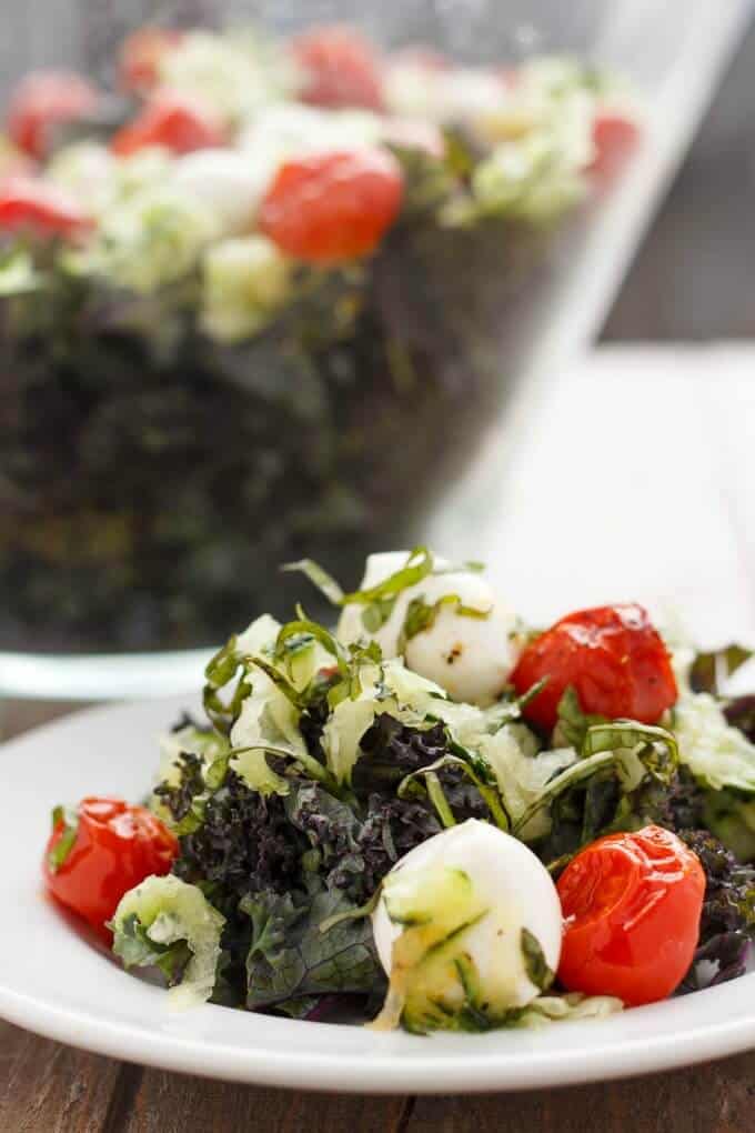 Roasted Tomato, Cucumber, and Bocconcini Salad on white plate and in big glass bowl in the background