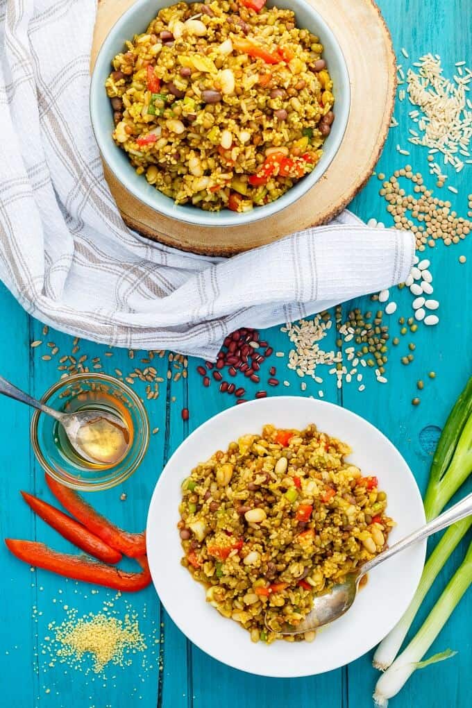 Summer Fresh Seven Grain Salad on white plate and in white bowl on blue table with many ingredients