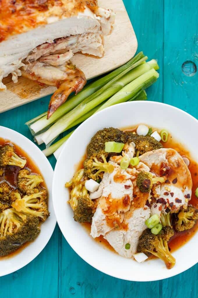 General Tso's Whole Chicken in the Slow Cooker on white plate and wooden pad, vegetable on blue table and on white plates