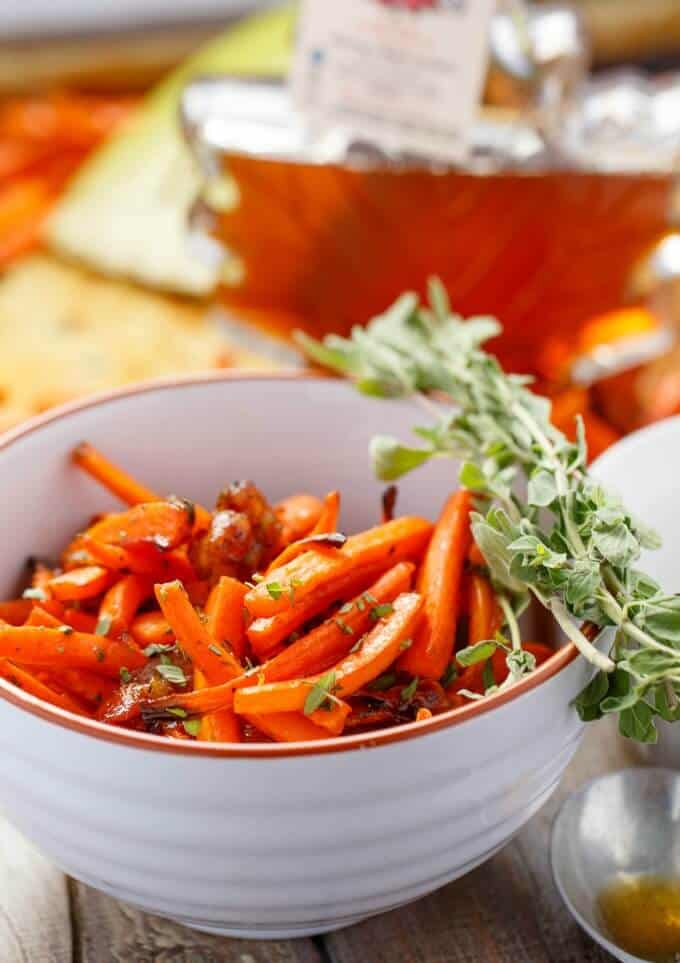 Maple bacon carrots in white bowl with herbs