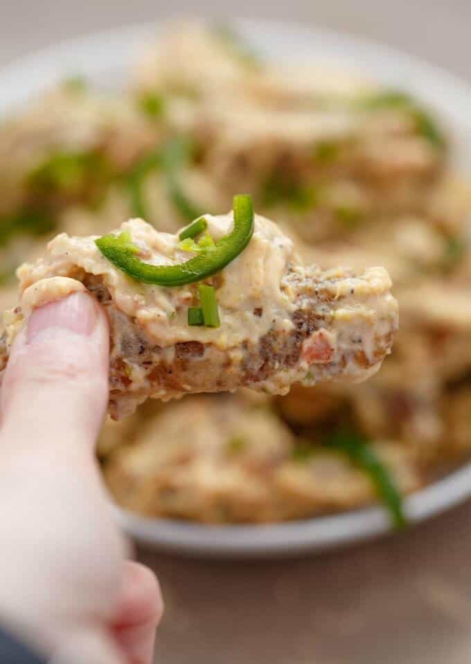 Jalapeno Popper Chicken Wings on white tray, one wing held by hand