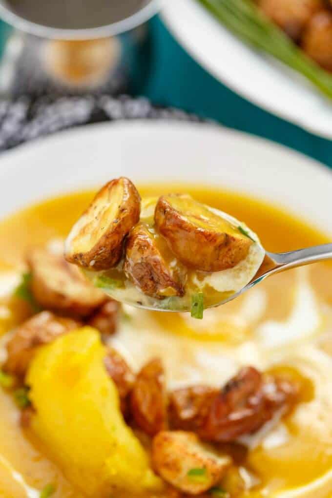 Roasted Apple Pumpkin Soup with Potatoes on white plate picked by spoon