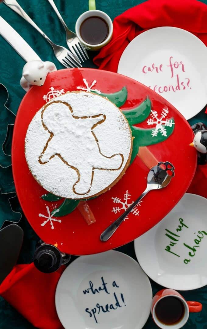 Gingerbread Cheesecake on chritmas themed tray with spoon next to white plates, forsk, coffe in cup