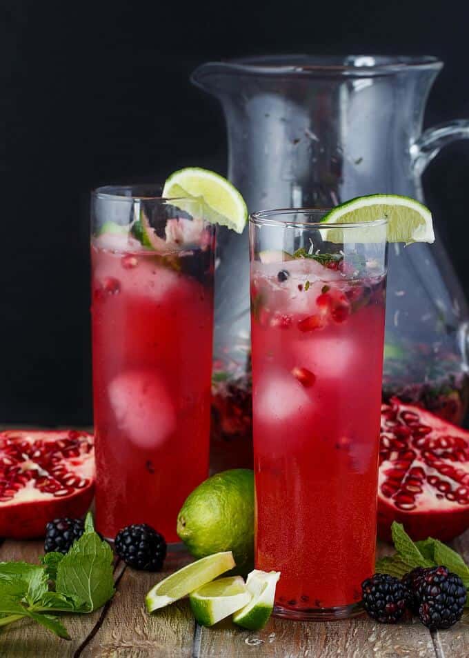 Pomegranate Blackberry Mojitos in glass cups and pitcher with lime slices,,blackberries,lime and pomegranate on the table