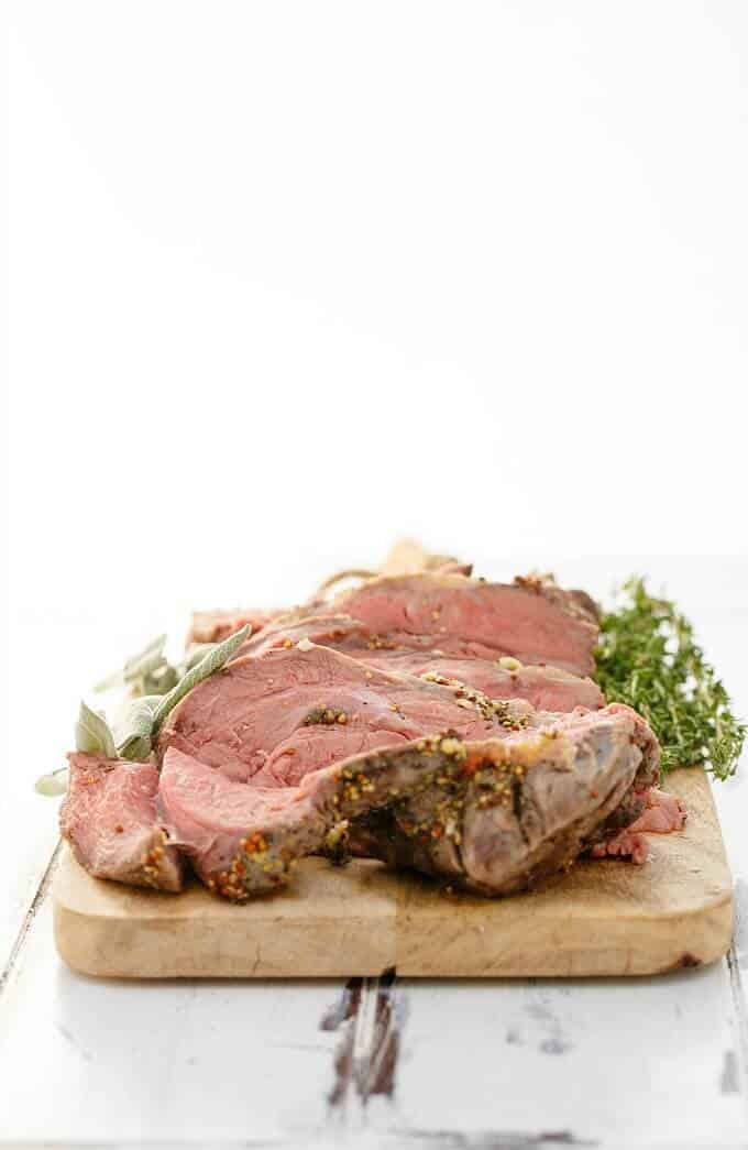 Slow Cooker Herb Butter Inside Round Roast on wooden pad with herbs