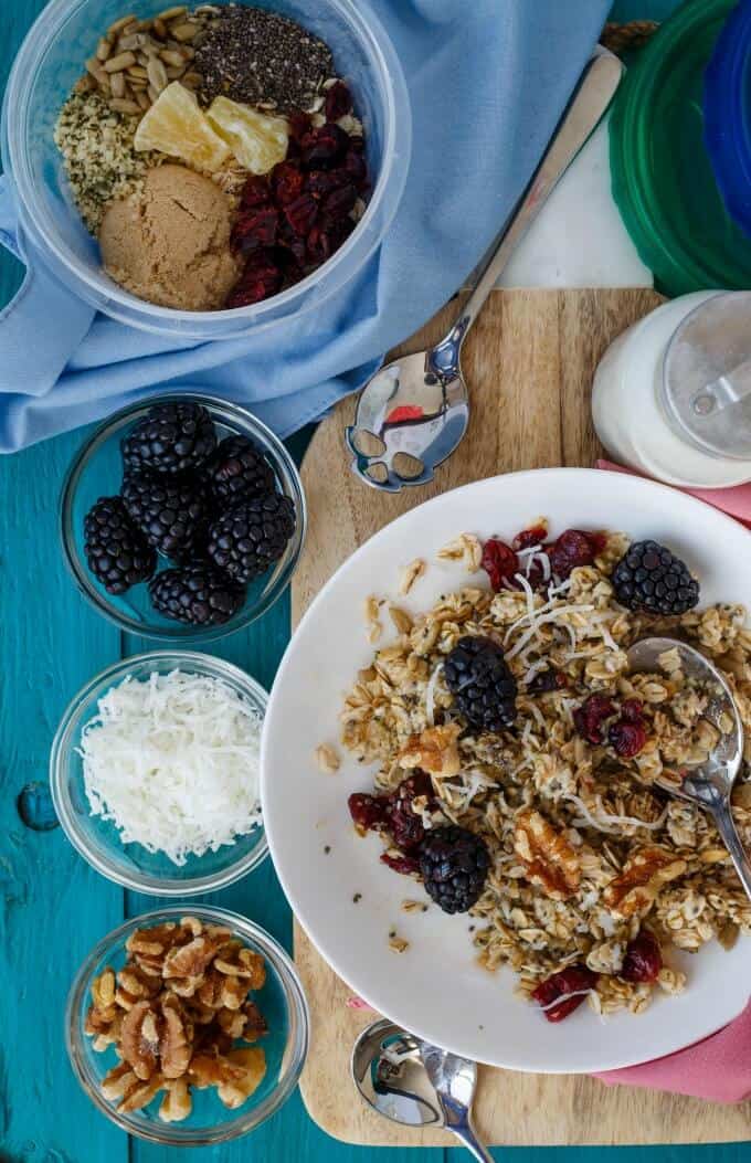 Homemade Instant Oatmeal on white plate with fruits and nuts , wooden pad, fruits, ramen, nuts in small bowls, jar with milk on the table